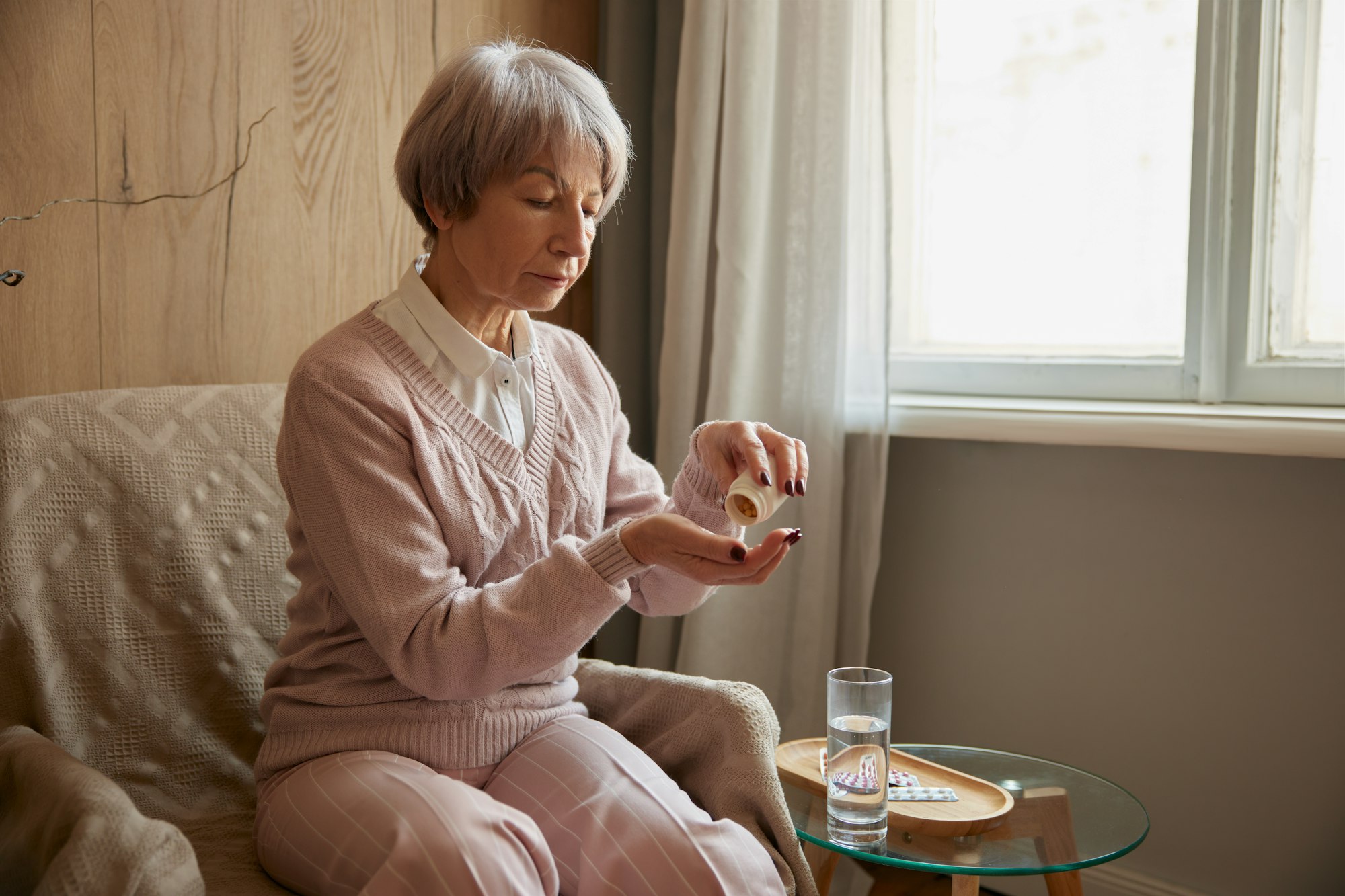 Elderly lady taking pills from chronic disease or multivitamins for health