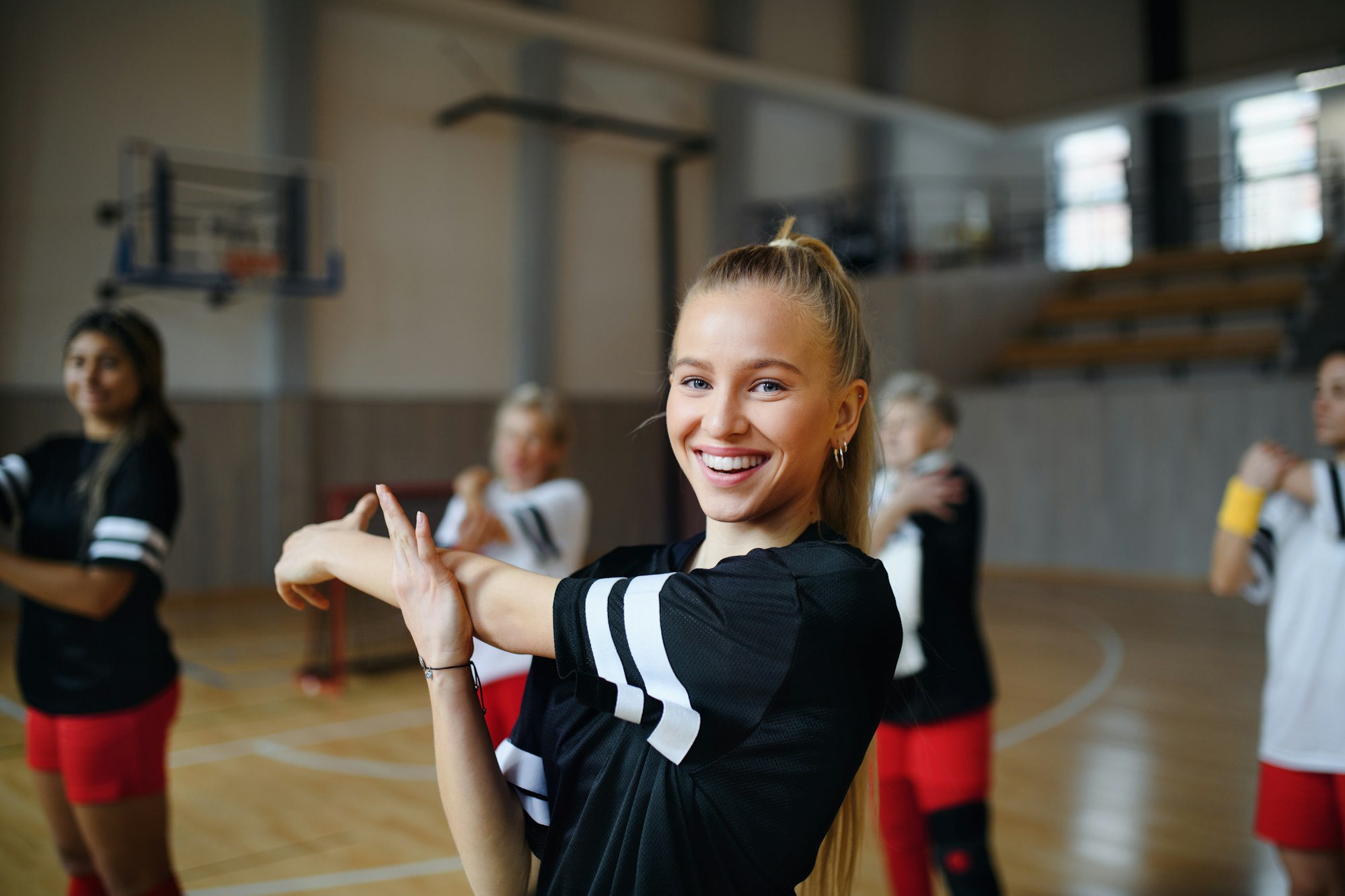 Group of multiaged women, sports team players. in gym stretching, warming up before match.