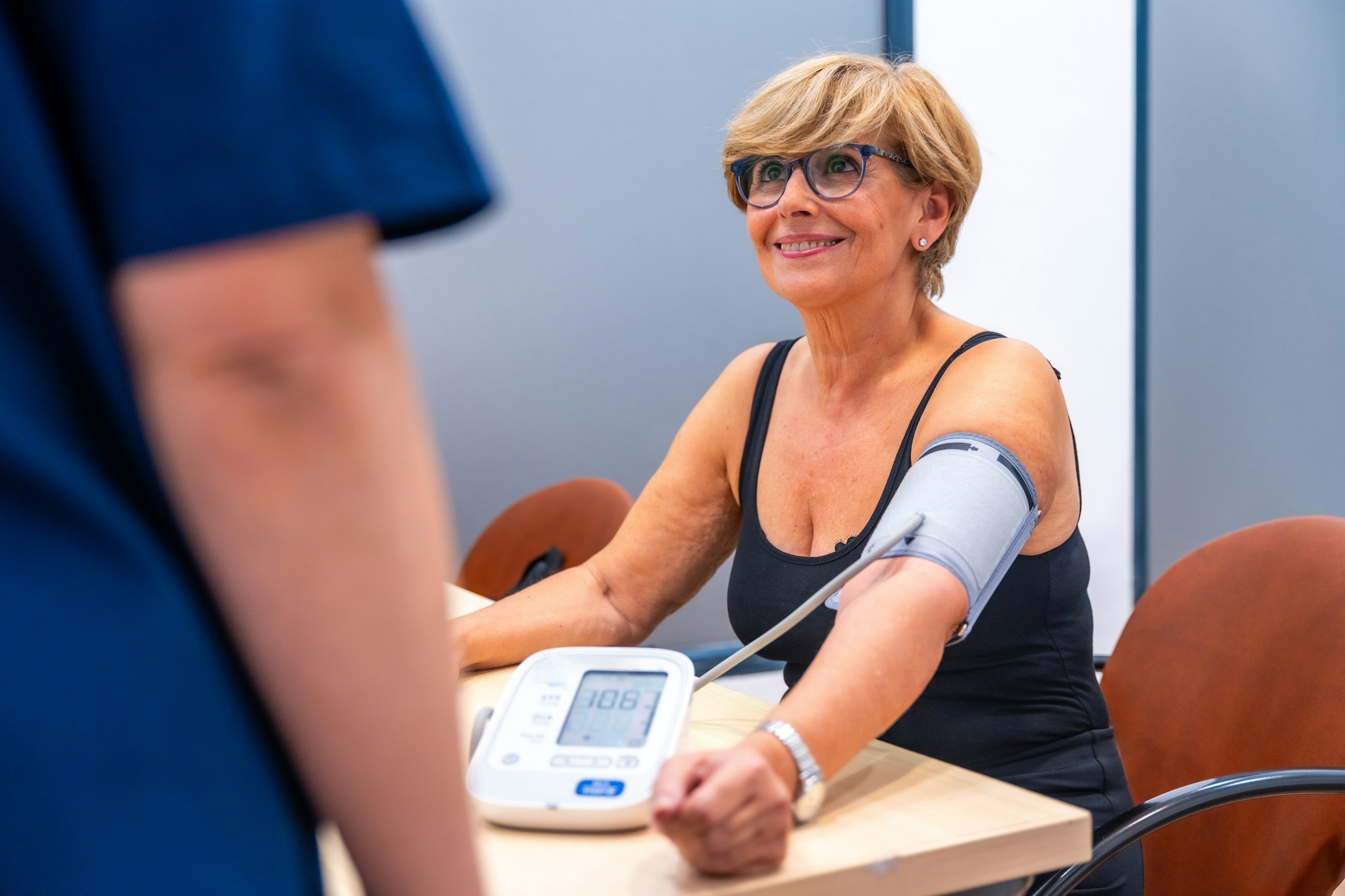 Smiling mature woman sitting during a blood pressure exam
